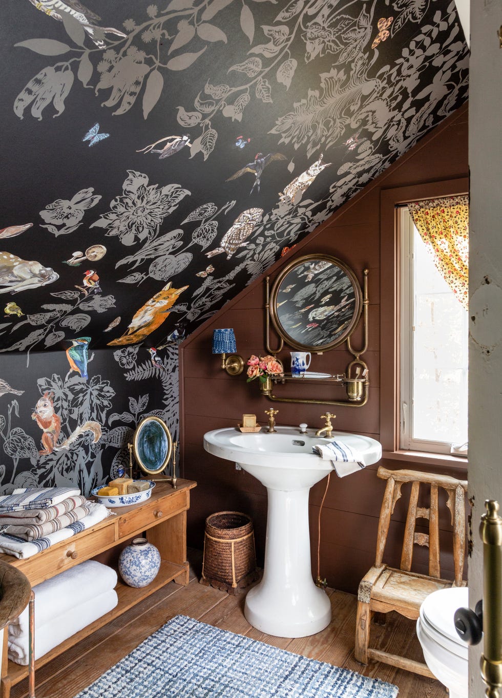 sloped roof bathroom with dark woodland creature themed wallpaper