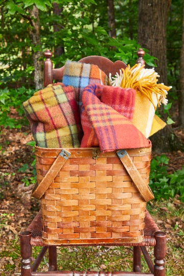 large antique picnic or gathering basket full of wool blankets