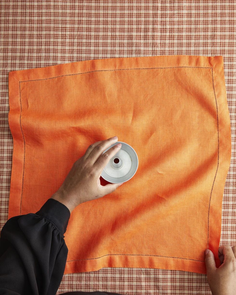 hands holding an orange napkin and mini bundt pan