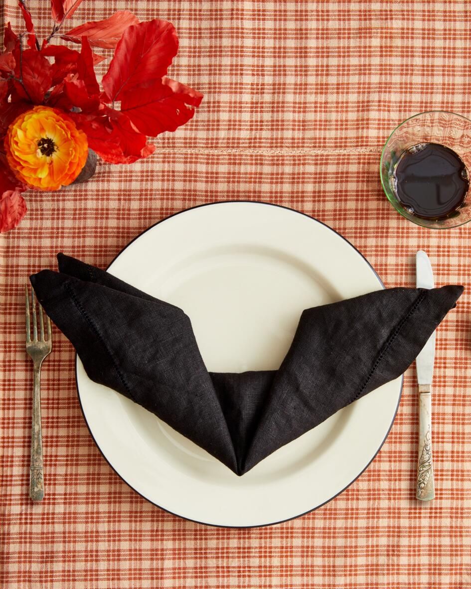 black napkin folded like a bat on table set for dinner