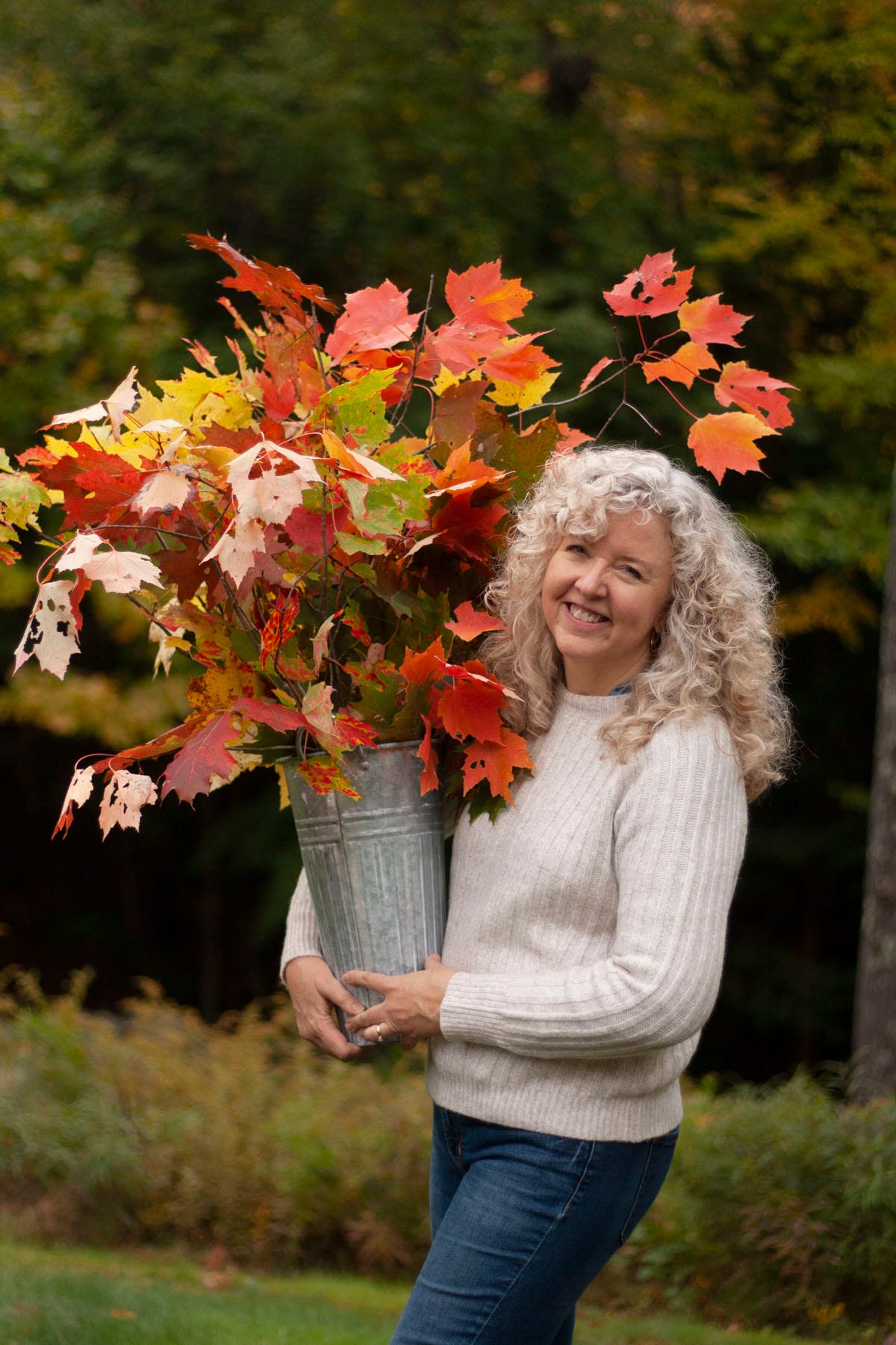 lady carrying a galvanized bucket full of fall branches