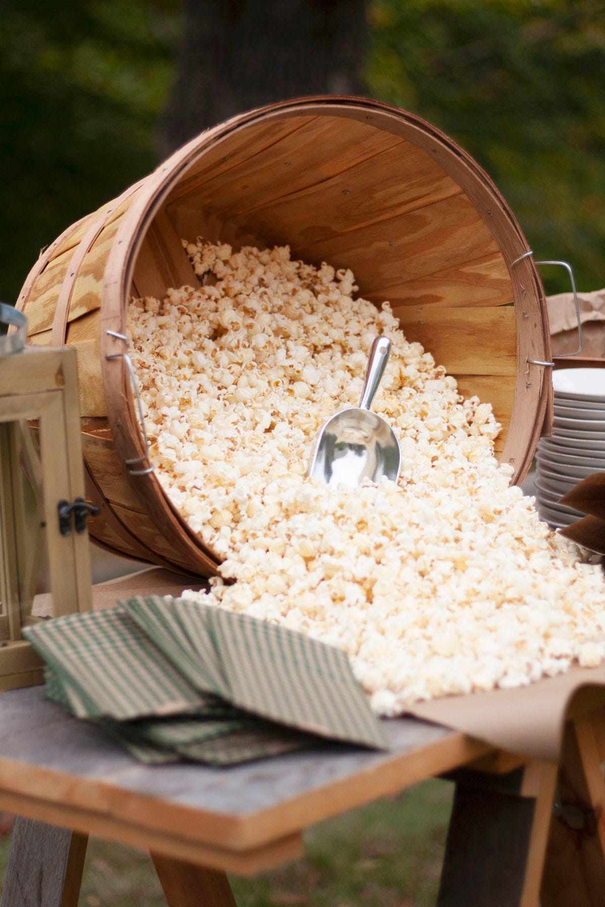 popcorn spilling out of an apple picking basket that has been set on its side on an outdoor buffet