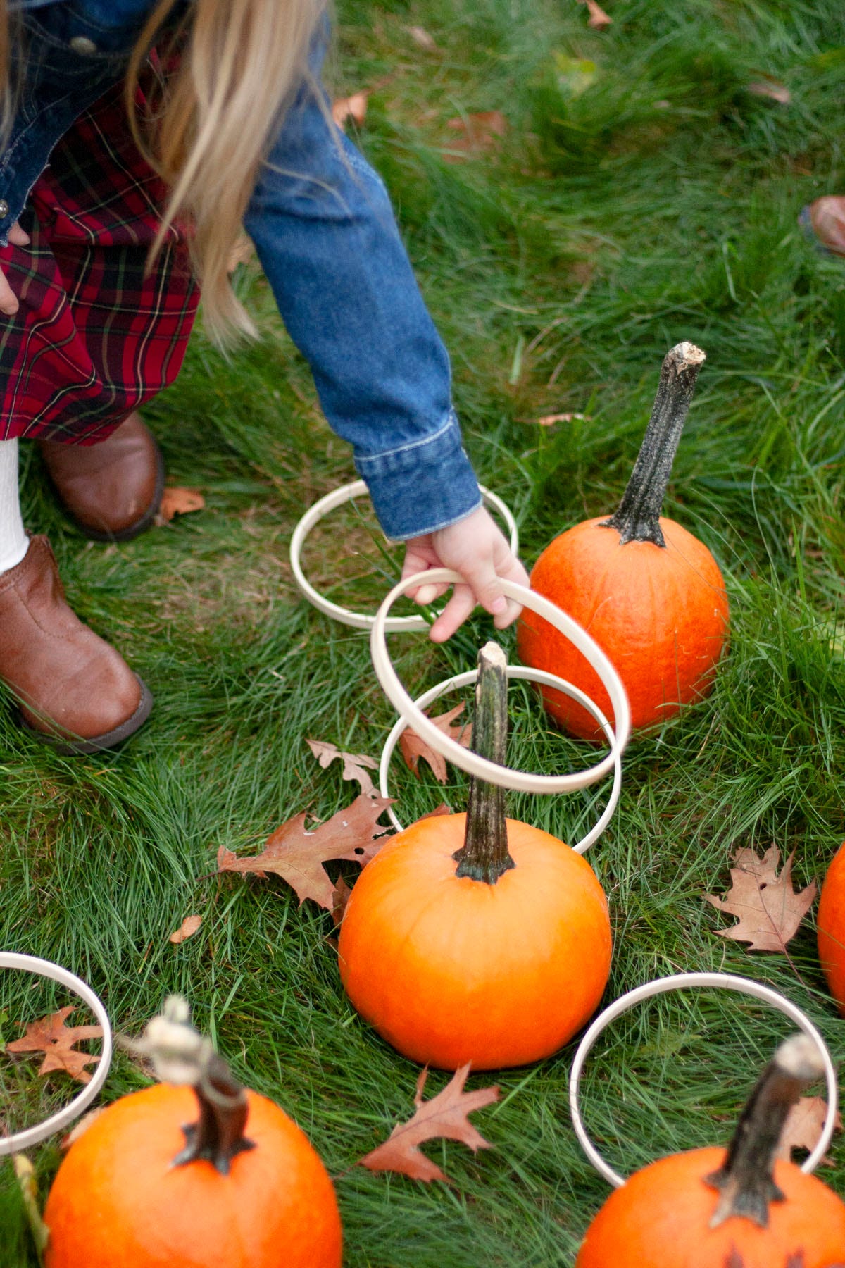 kids playing ring toss with pumpkins embroidiery hoops all set in the grass with fall leaves