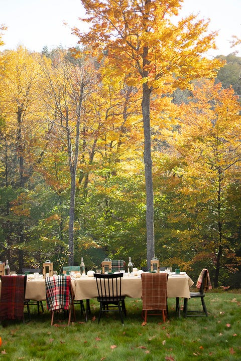 a table set outside with a white tablecloth and blankets on the chairs