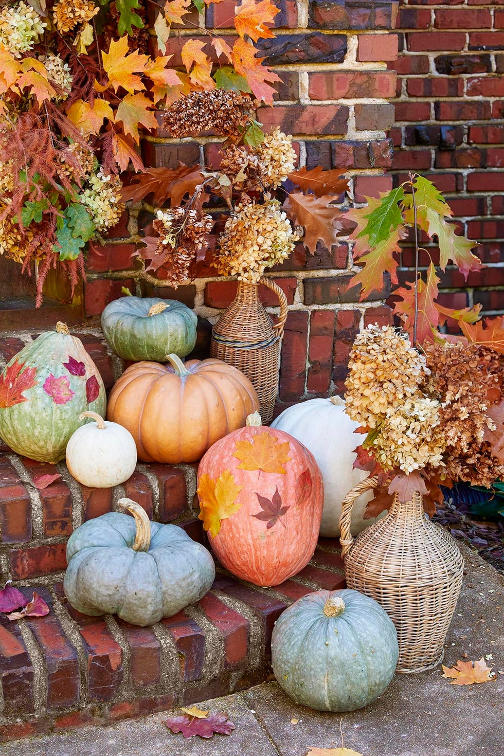 pumpkins decorated with fall leaves cascade down the steps and are paired with vintage wicker demijohns