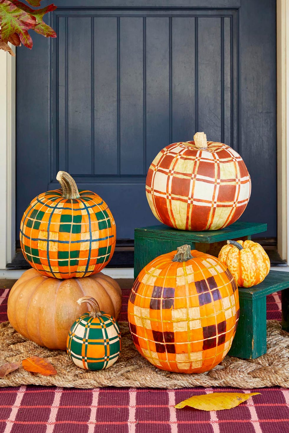 pumpkins decorated to look like plaid blankets set in front of a blue door