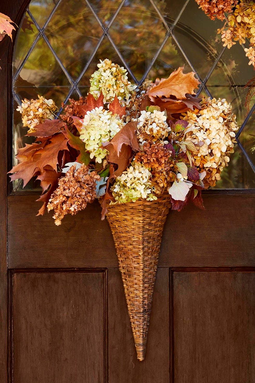 dried hydrangea and leaves in a cone shaped basket hung on a brown door