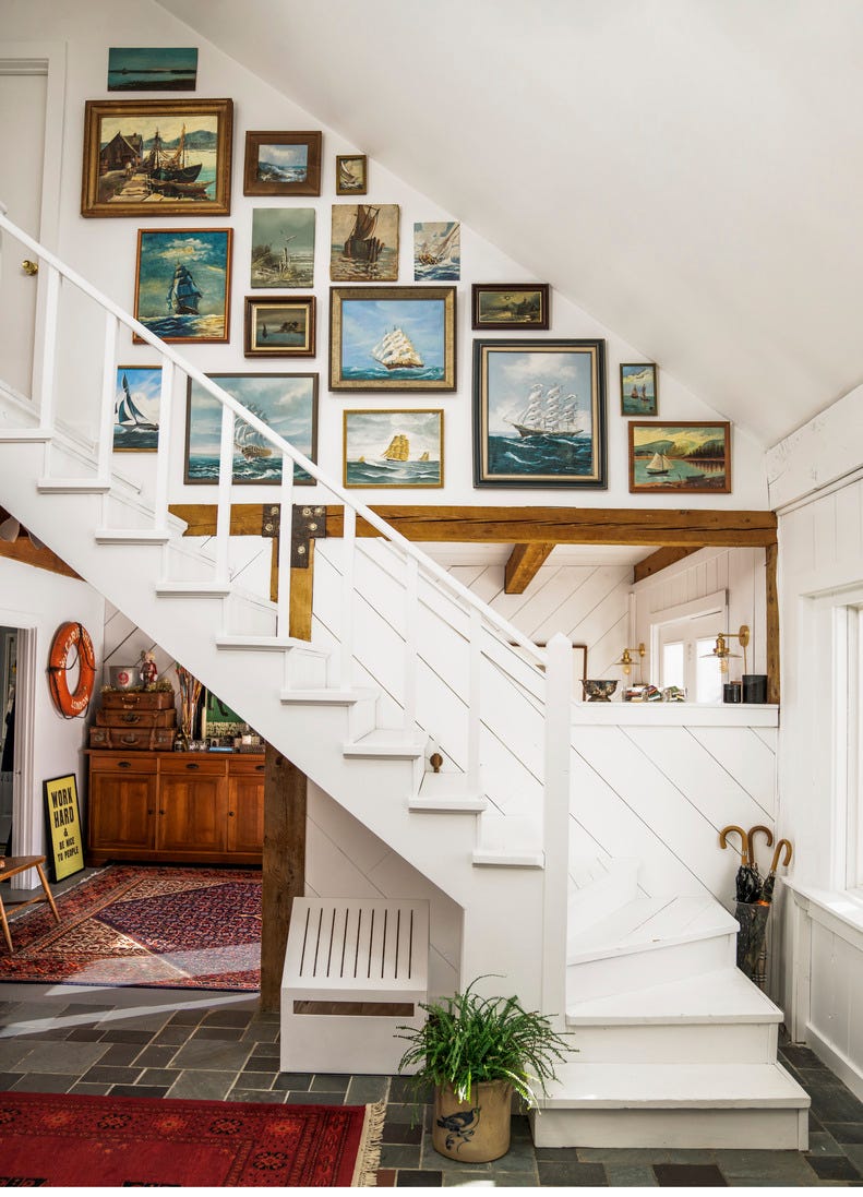 white staircase with lots of nautical oil paintings