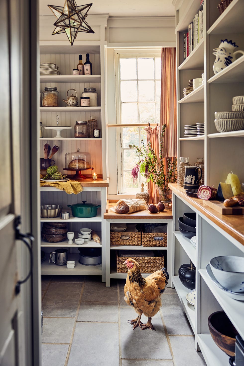 pantry with open shelving, flagstone floors with chicken in foreground