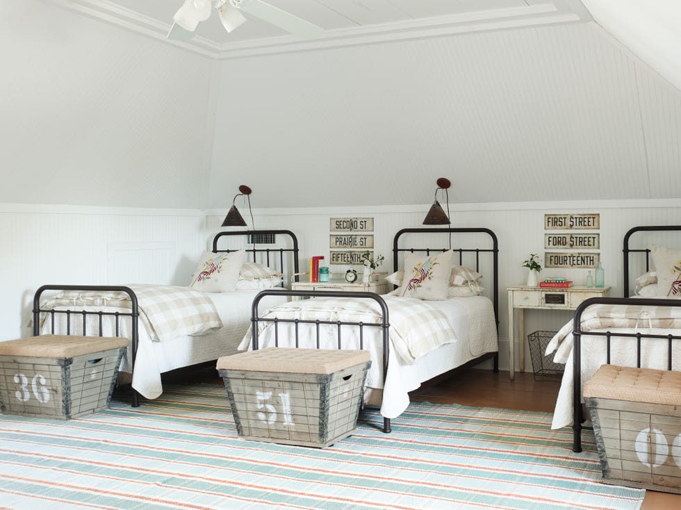 guest room with three iron twin beds and antique laundry hampers at the foot of each bed