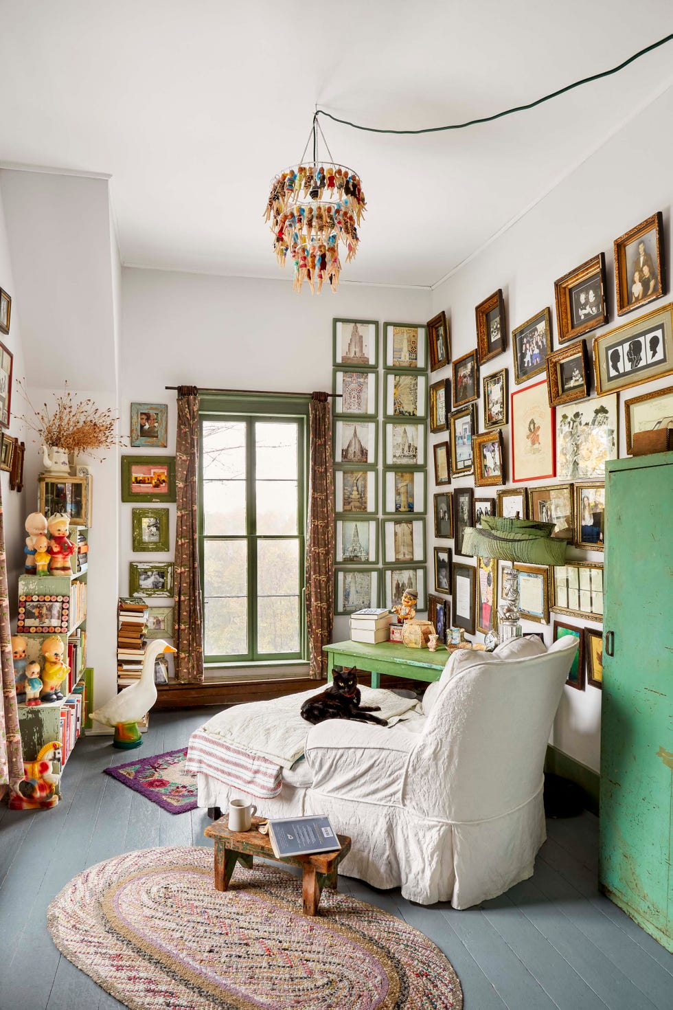 small room filled with artwork and a white chaise