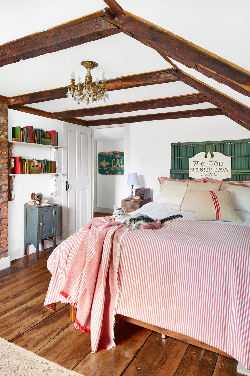 white bedroom with red and white bedding and green shutters as the headboard