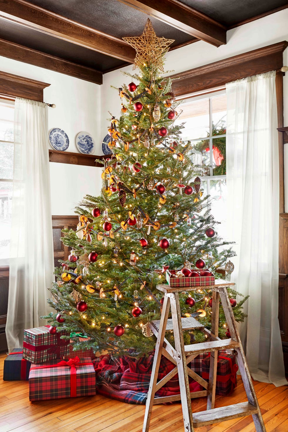 traditional christmas tree with rattan star topper with rustic wood ladder holding ornaments