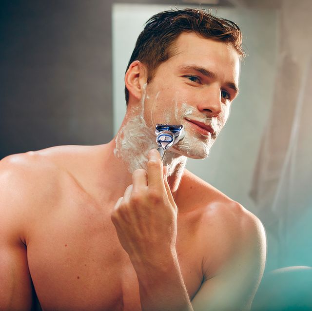 un hombre joven y muy guapo se afeita delante del espejo para ilustrar un tema sobre cómo conseguir el afeitado perfecto con gillette skinguard