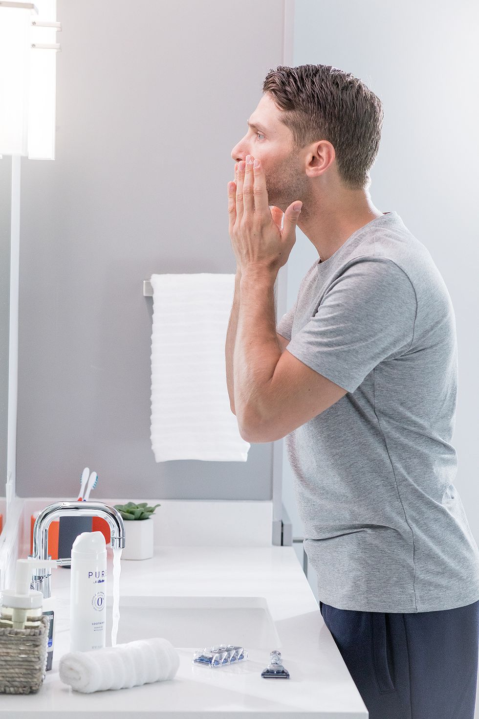 un hombre joven frente al espejo se prepara para afeitarse con productos skinguard de gillette