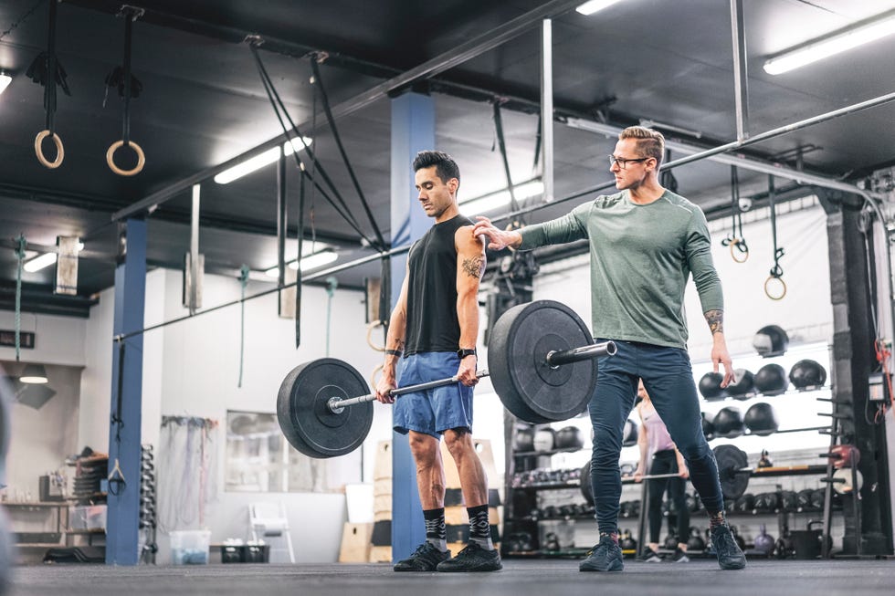 coach assisting male athlete during weightlifting