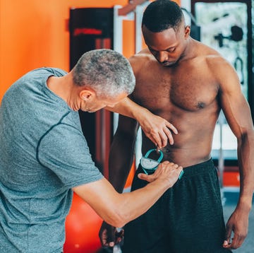 coach measuring client's body fat with caliper