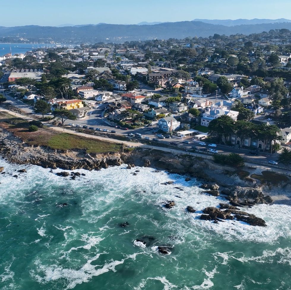 an aerial view of a rocky coastline with a road and town