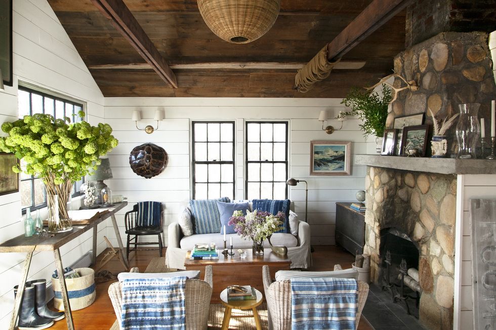 coastal living room with a loveseat and chairs and a stone fireplace