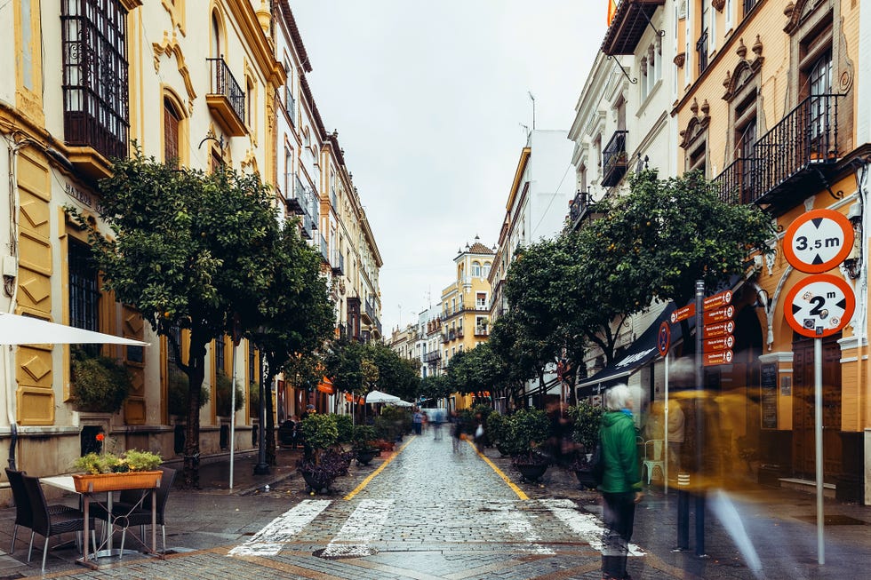 Cobbled street of Seville with colorful buildings, Spain"n