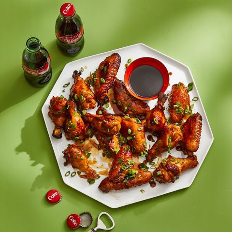 coca cola chicken wings on a white platter with green background