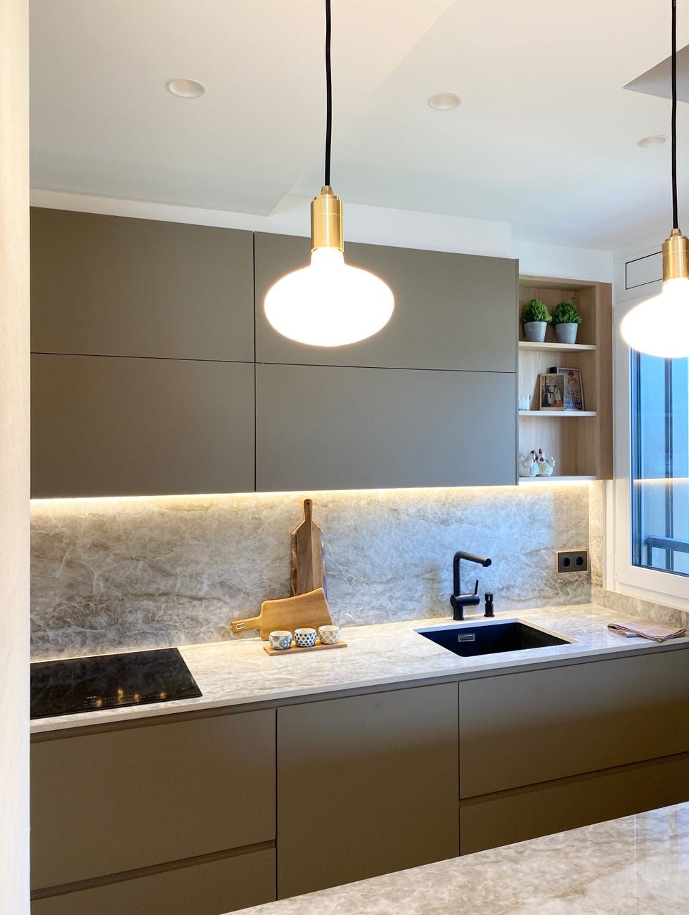 cocina abierta al salón diseñada en color gris con armarios sin tiradores y encimera dekton efecto mármol gris