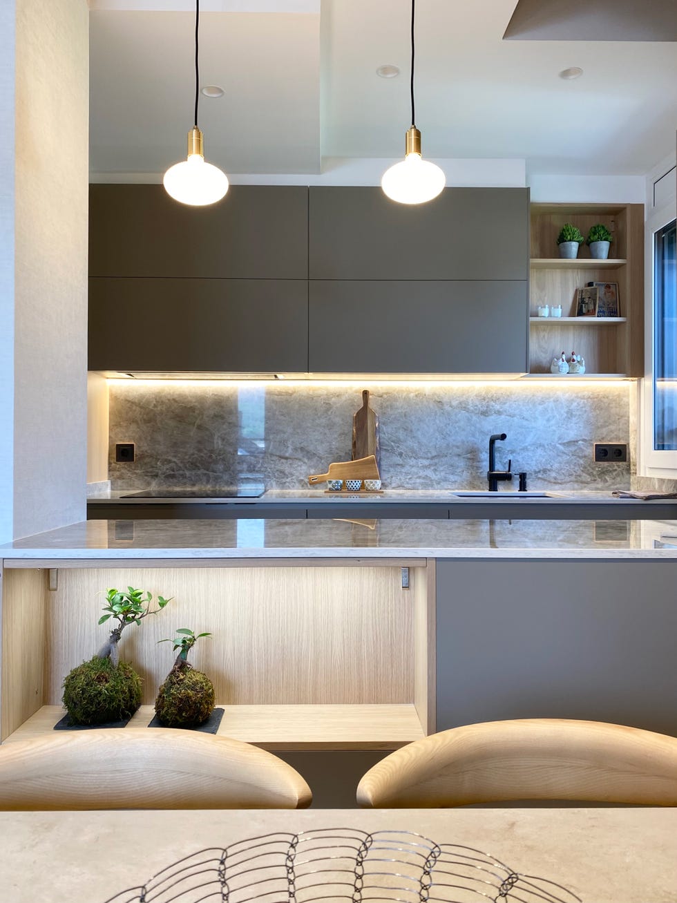 cocina abierta al salón diseñada en color gris con armarios sin tiradores y encimera dekton efecto mármol gris