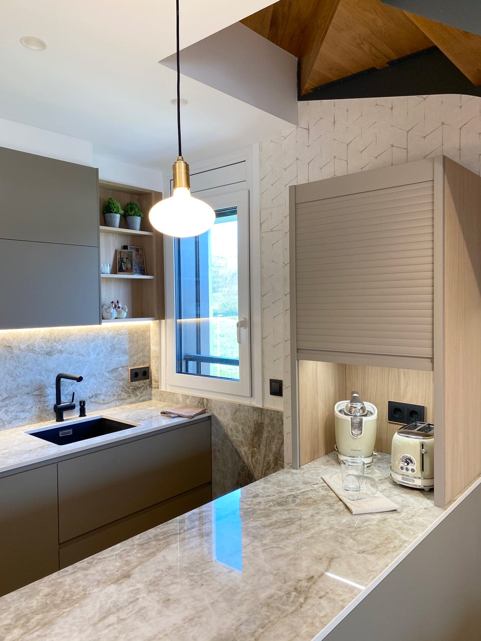 cocina abierta al salón diseñada en color gris con armarios sin tiradores y encimera dekton efecto mármol gris