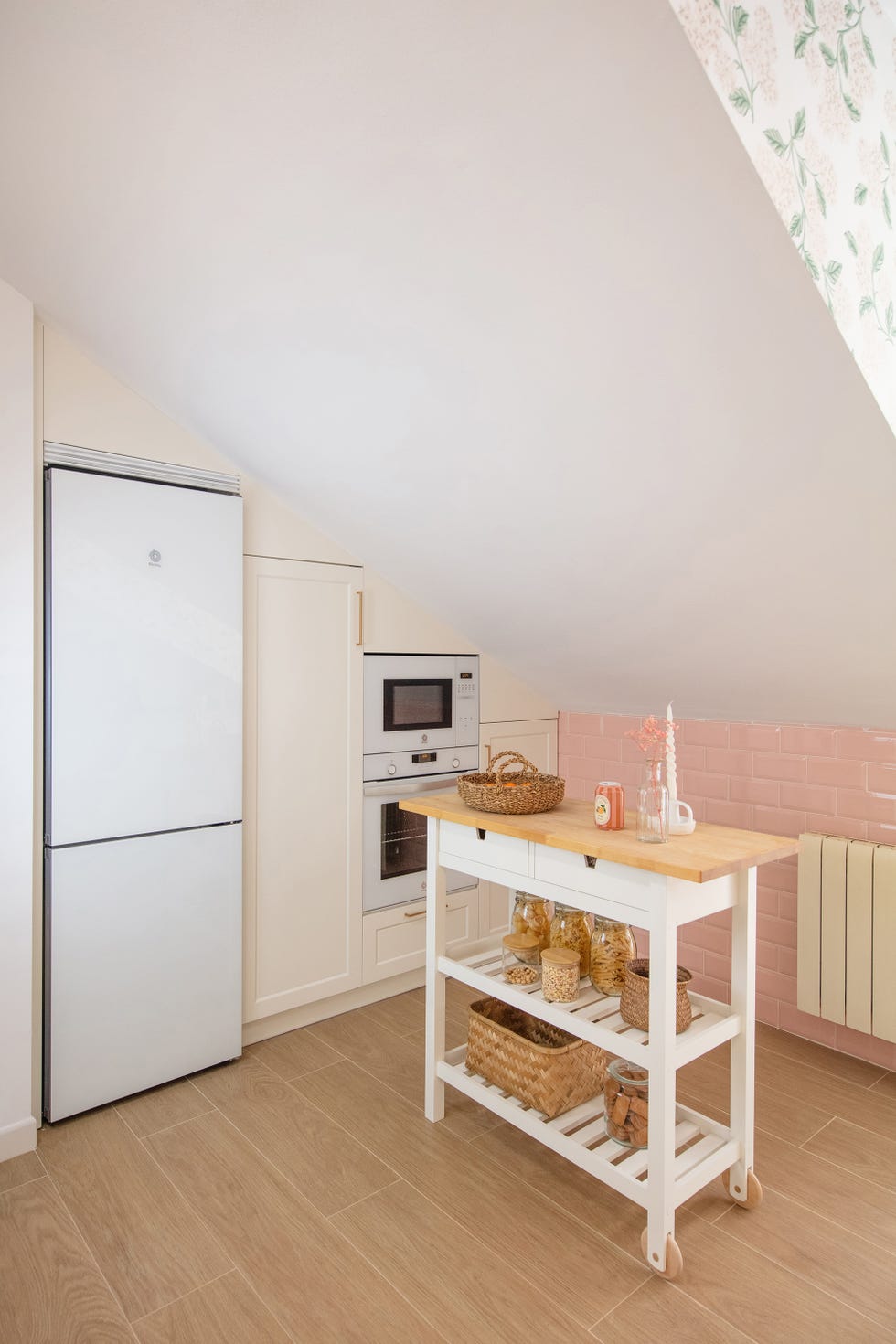 cocina abuhardillada con armarios y electrodomésticos blancos y carrito con ruedas