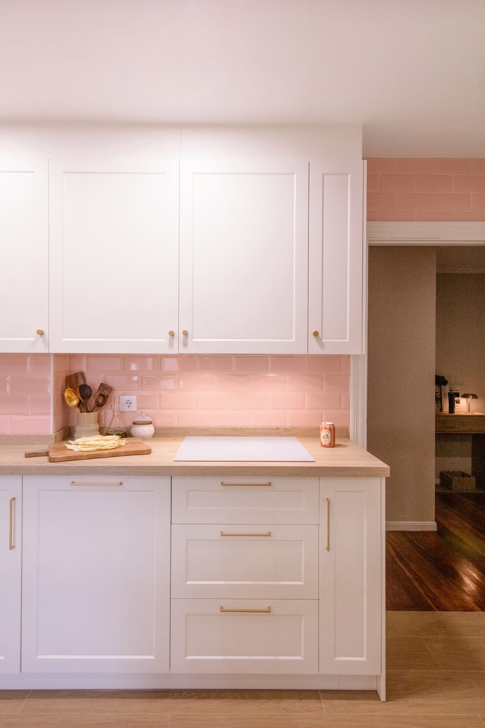 cocina con armarios blancos y frente de azulejos rosas