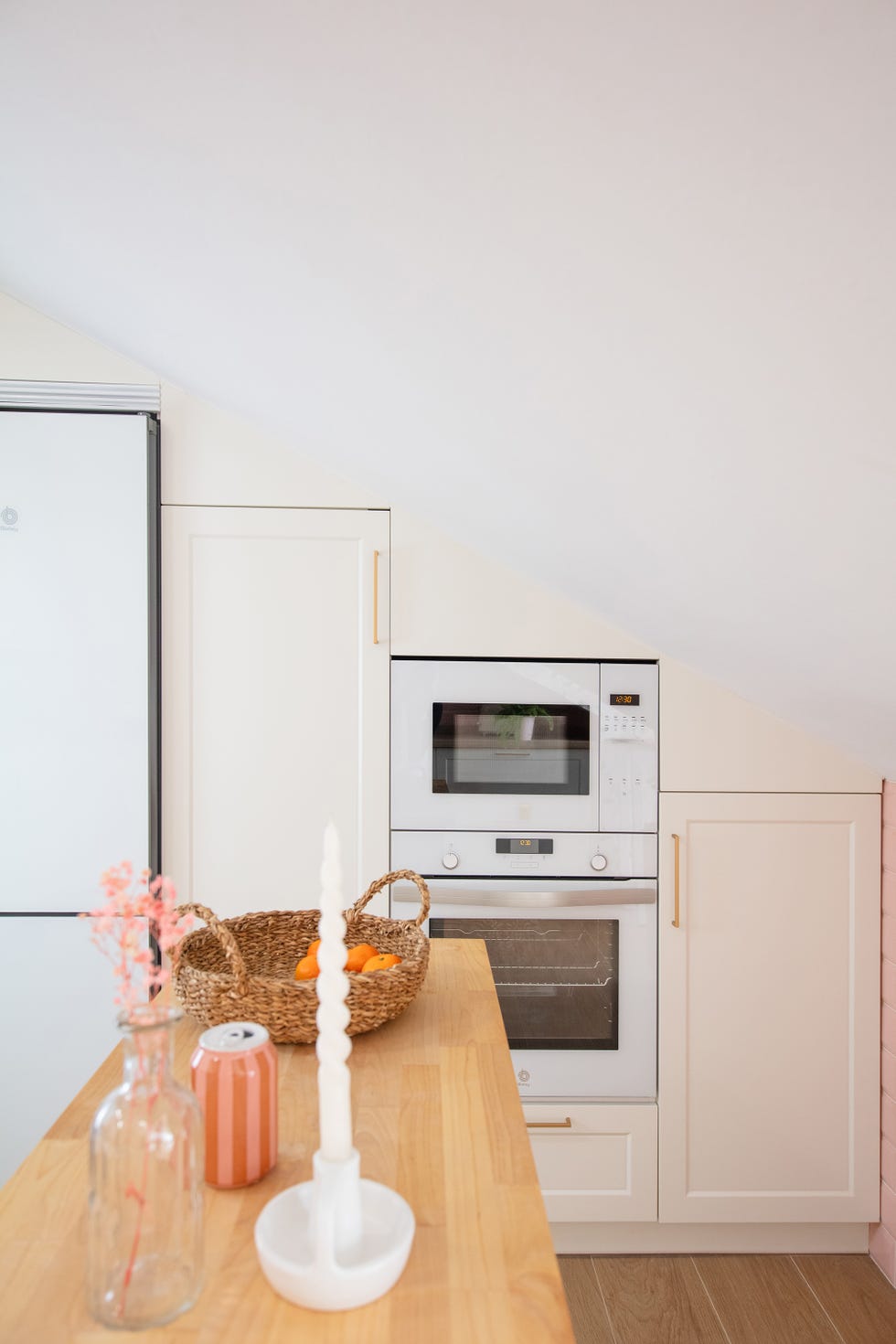 cocina abuhardillada con armarios y electrodomésticos blancos