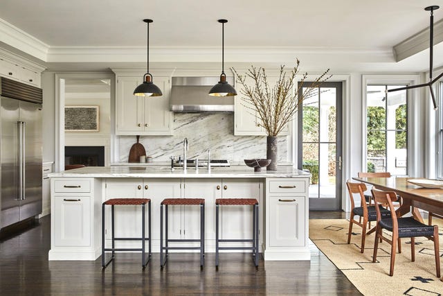 una cocina con isla y comedor con muebles de almacenaje blancos