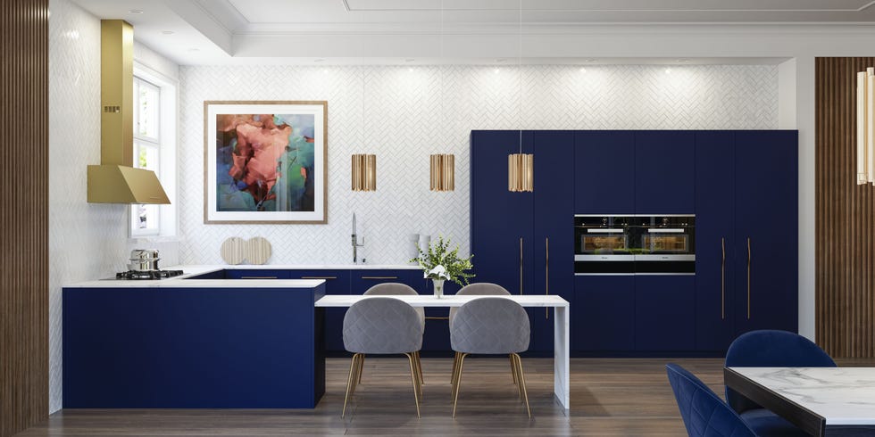 cocina con península y mesa de comedor con armarios de color azul intenso y tiradores dorados