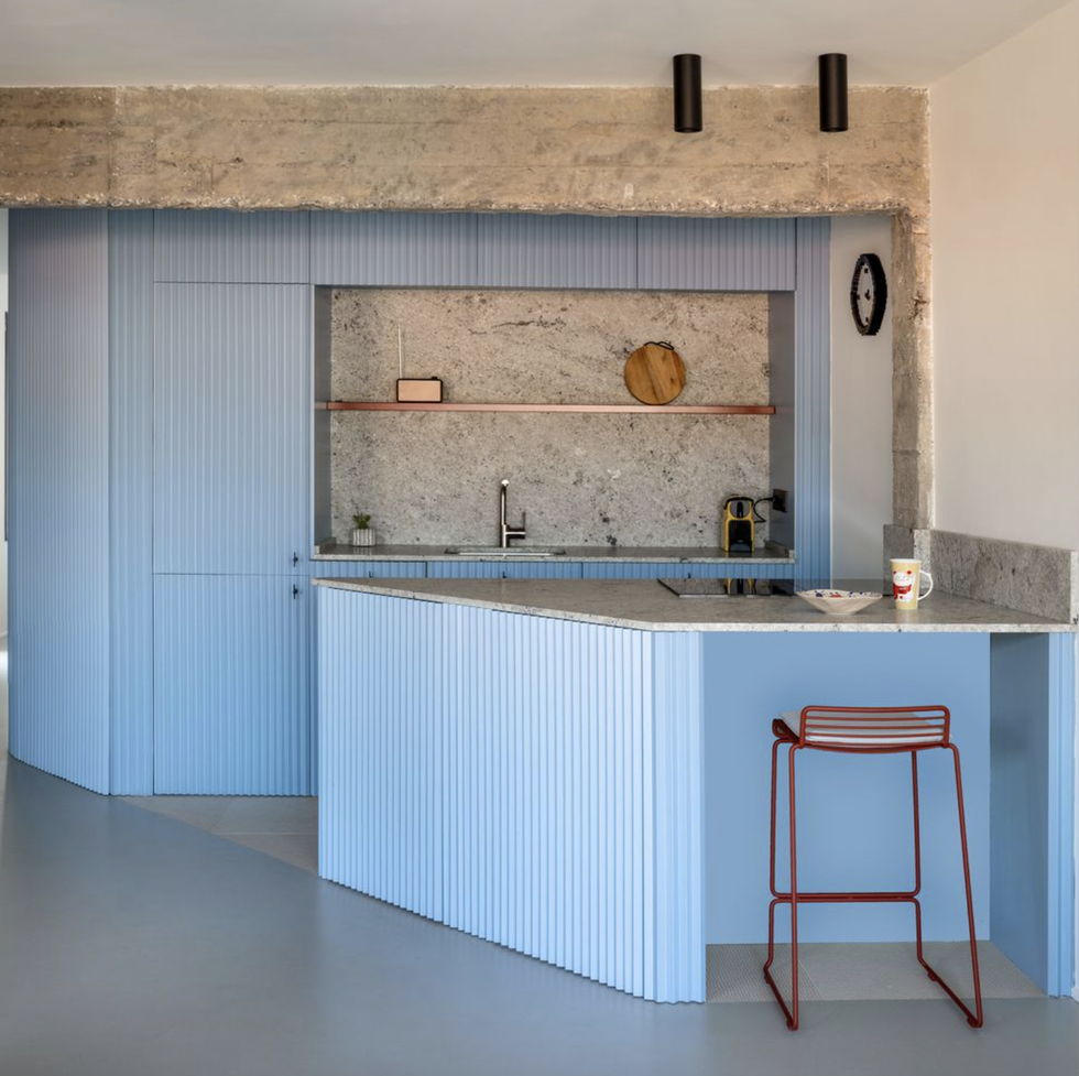 Una cocina decorada en color azul con isla central y office