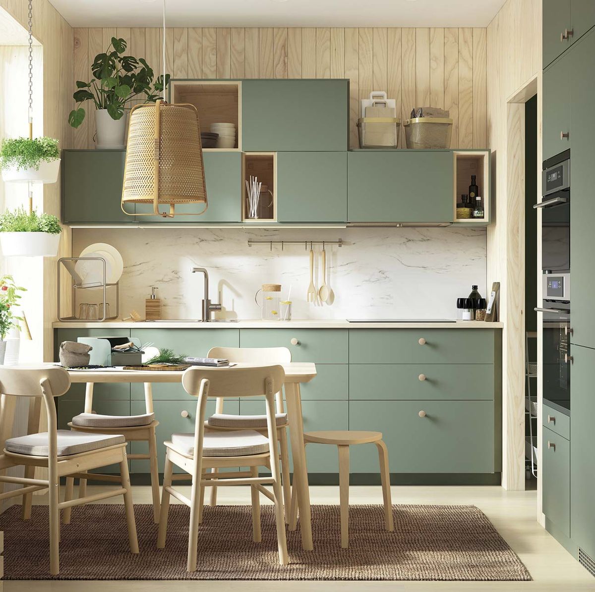 Una cocina con un mueble de cocina verde con tiradores dorados y una  encimera de mármol blanco.