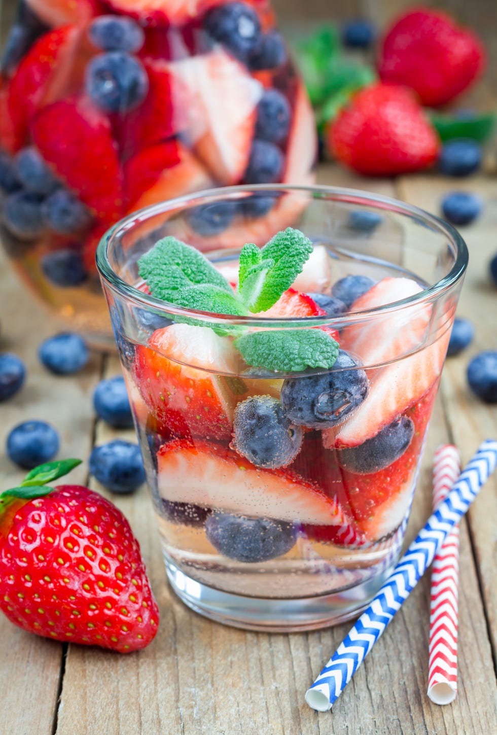 cocktail with strawberry and blueberry on a wooden table, vertical