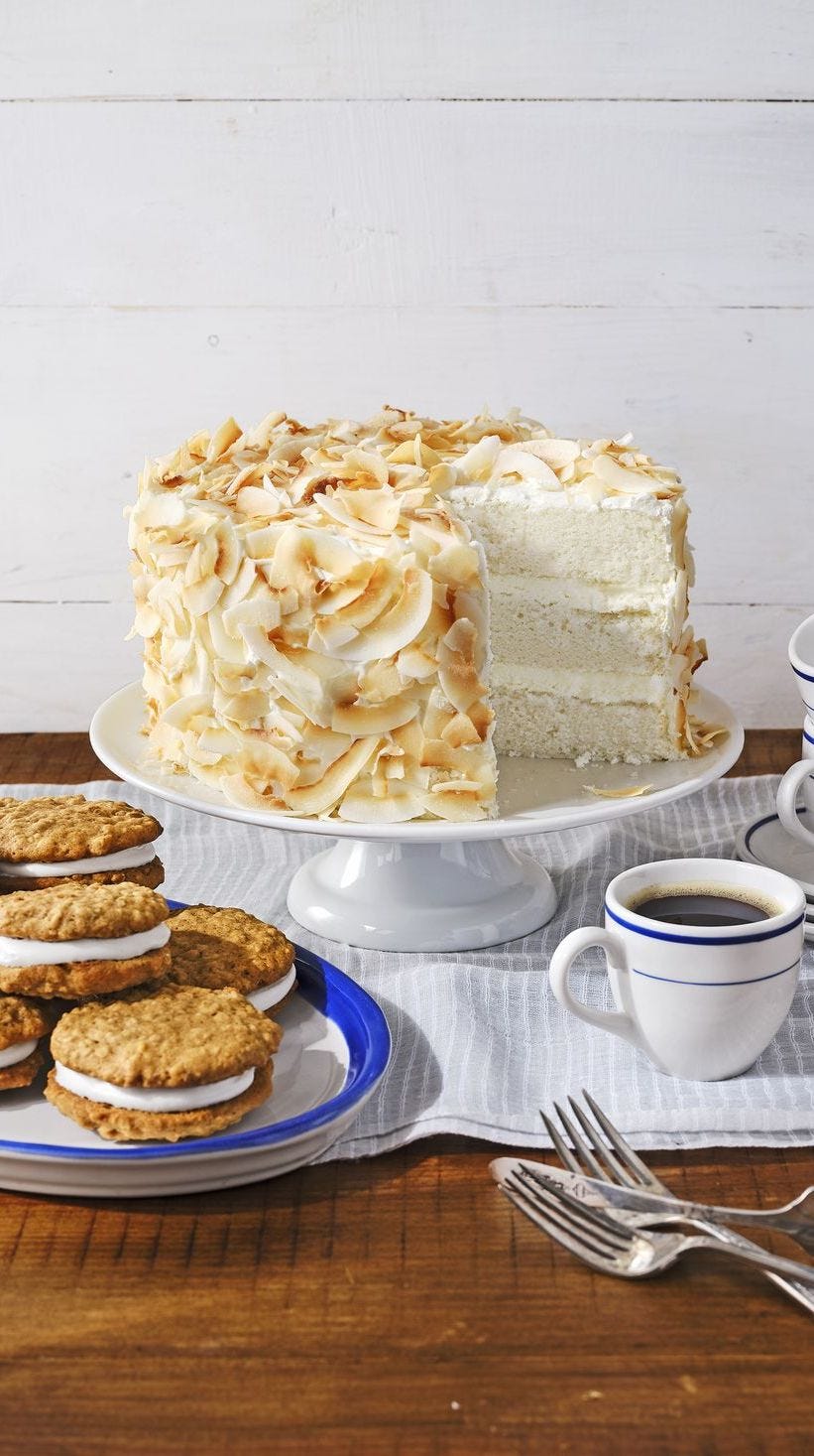 coconut angel cake on a white cake stand with a mug of coffee