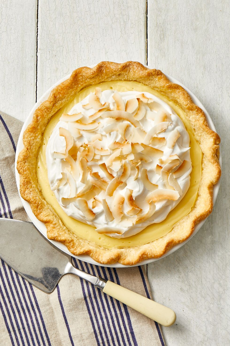 coconut cream pie on a wooden table, next to a serving knife