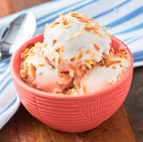 coconut ice cream topped with toasted coconut shavings in a pink bowl