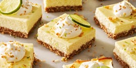 coconut key lime cheesecake bars with whipped cream, shredded toasted coconut, and lime