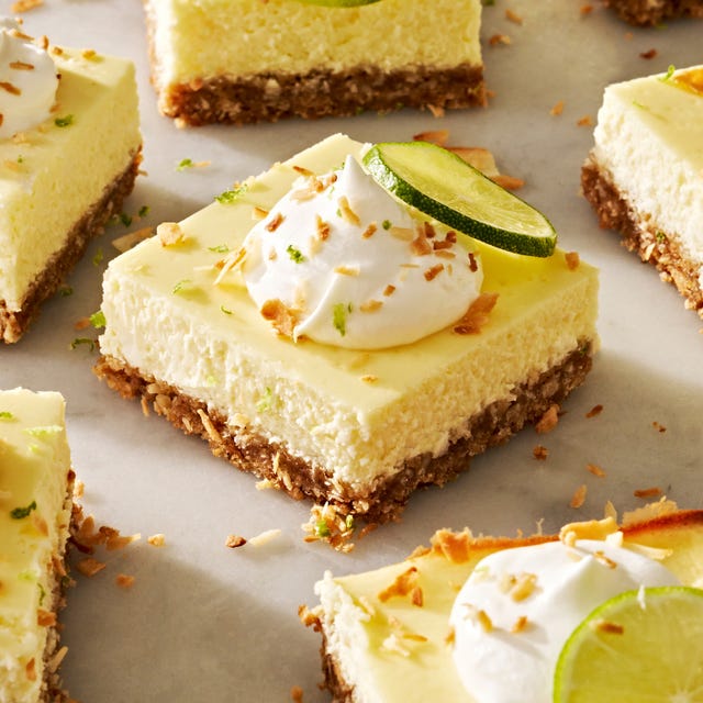 coconut key lime cheesecake bars with whipped cream, shredded toasted coconut, and lime