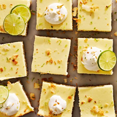 coconut key lime cheesecake bars with whipped cream, shredded toasted coconut, and lime