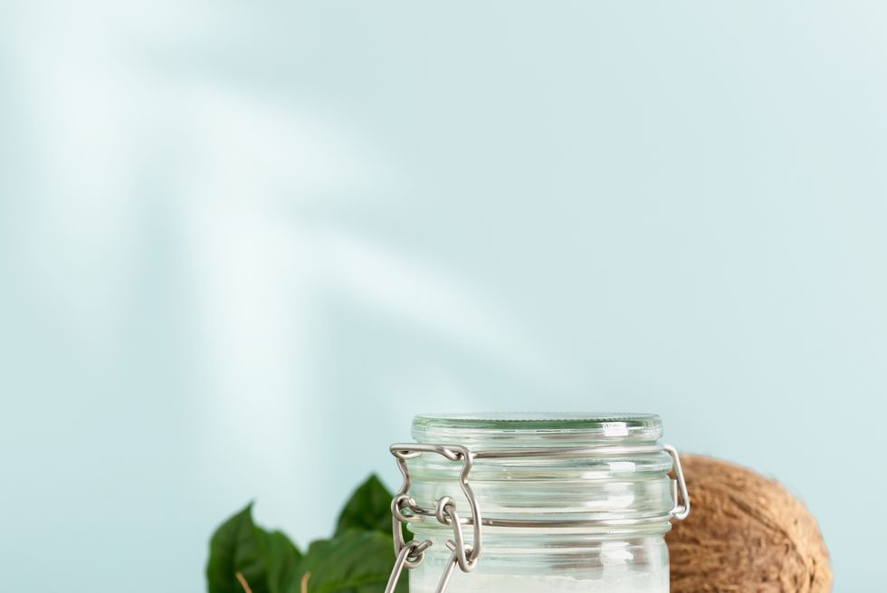 coconut oil in jar with fresh coconut and tropical leaf shadow,square composition,romania