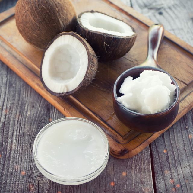 Coconut with coconut oil in jar on wooden background