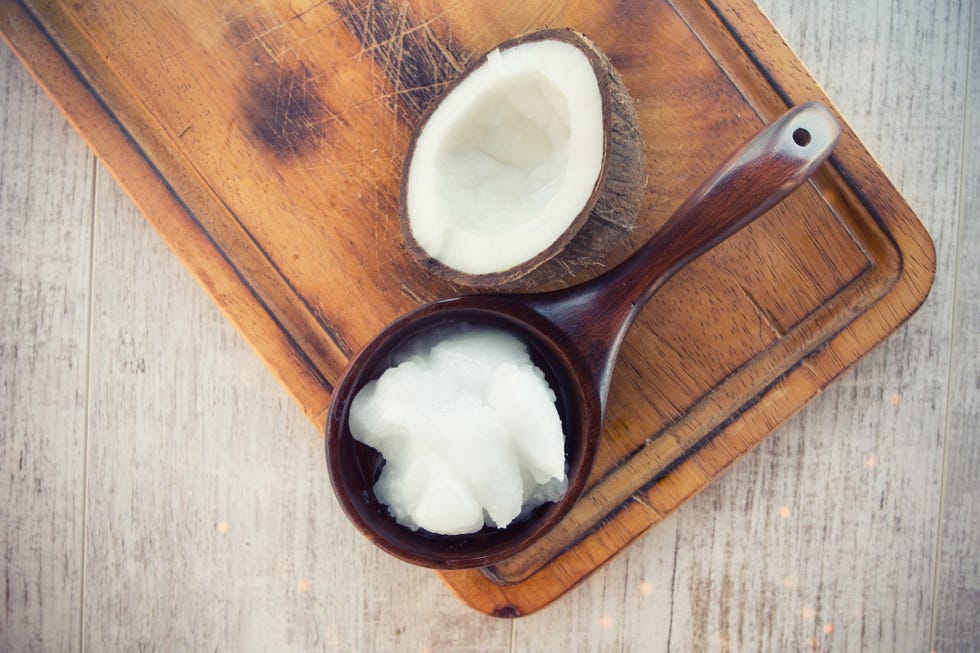 Coconut with coconut oil in jar on wooden background