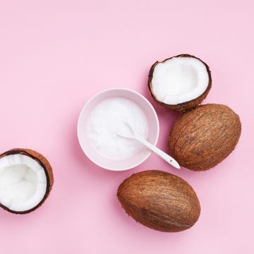 Coconuts fruit with coconut oil on pink pastel table top view. Beauty and spa organic cosmetic. Flat lay.