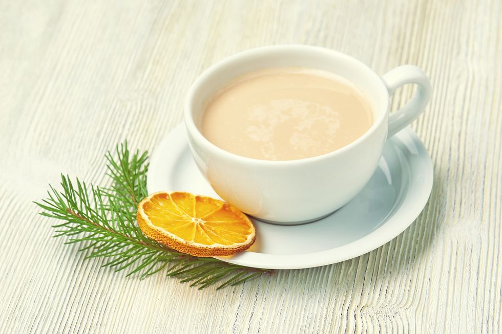 coffee cup cappuccino and saucer on a light wooden background decorated with fir branch and dried orange slice christmas morning