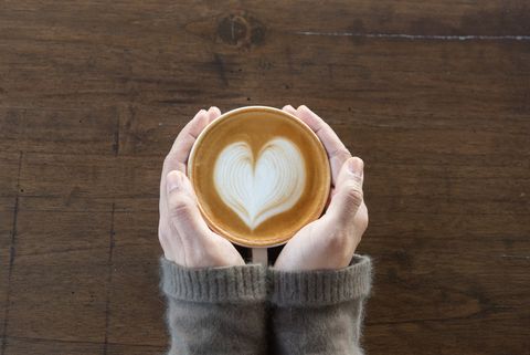 coffee cup in coffee shopfemale hands holding cup of coffee on wooden table background