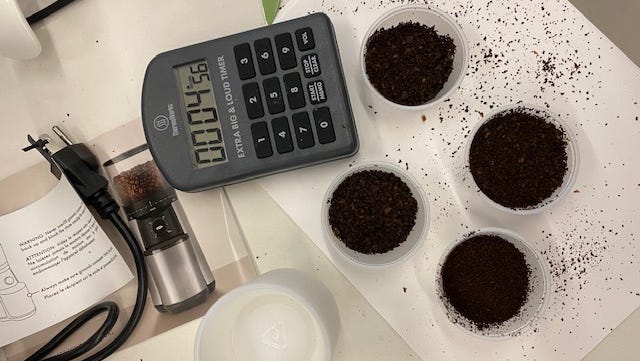 Best coffee grinder- coffee grinder testing ground coffee in cups shown with a calculator and instruction manual for coffee grinder testing