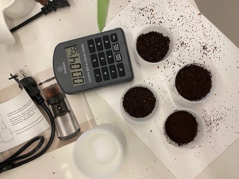 ground coffee in cups shown with a calculator and instruction manual for coffee grinder testing